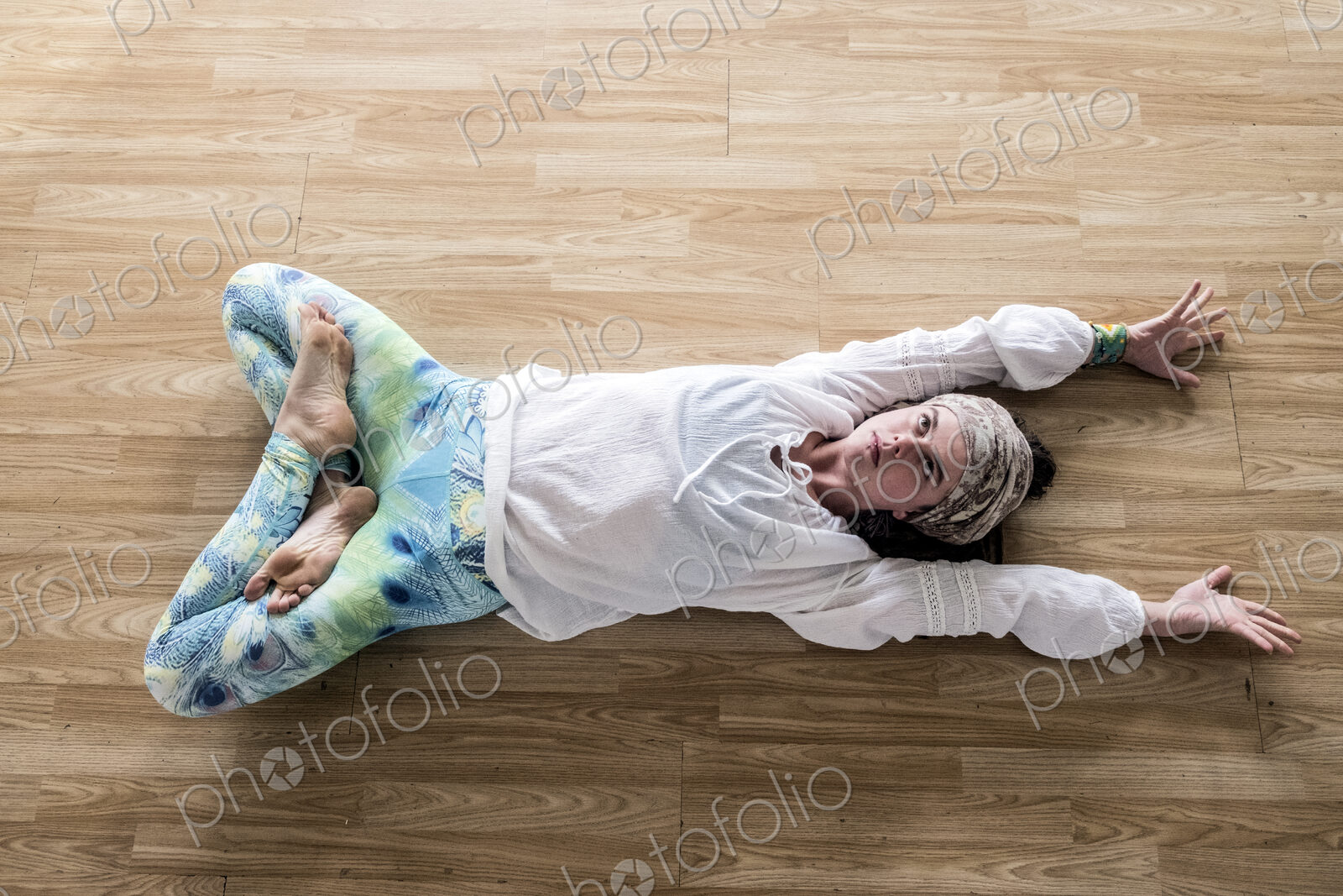 High angle view of young woman wearing headscarf and white blouse lying on her back on…