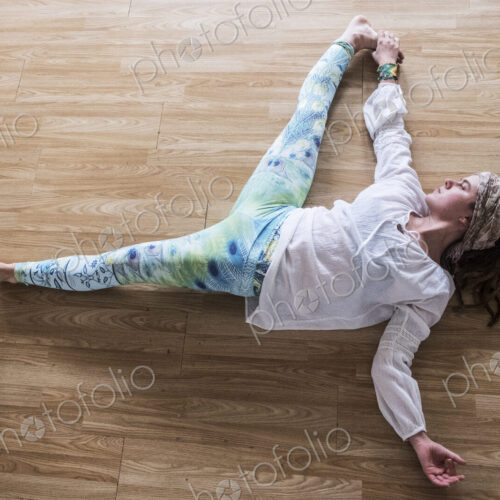 High angle view of young woman wearing headscarf and white blouse lying on her back on…