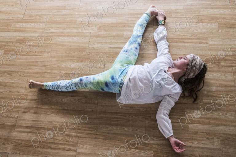 High angle view of young woman wearing headscarf and white blouse lying on her back on…