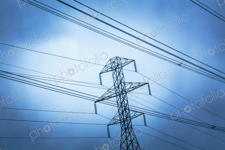 High transmission tower and wires seen from a low angle, overhead power cables.