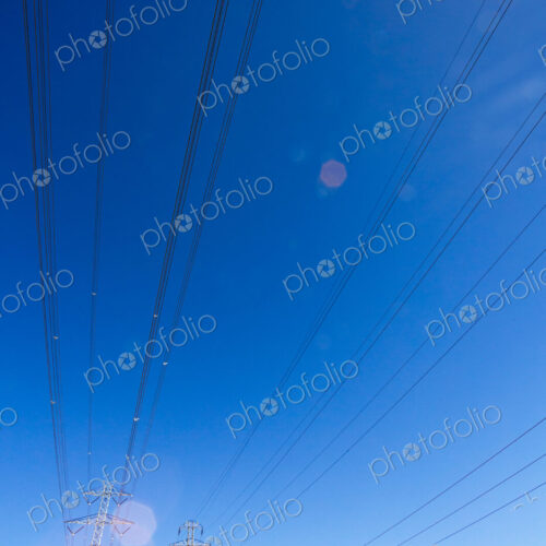 High transmission towers and lines over a dry hillside.
