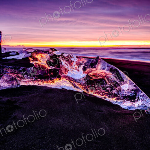Hiker admiring glaciers on beach reflecting sunset sky Hiker admiring glaciers on beach reflecting sunset sky