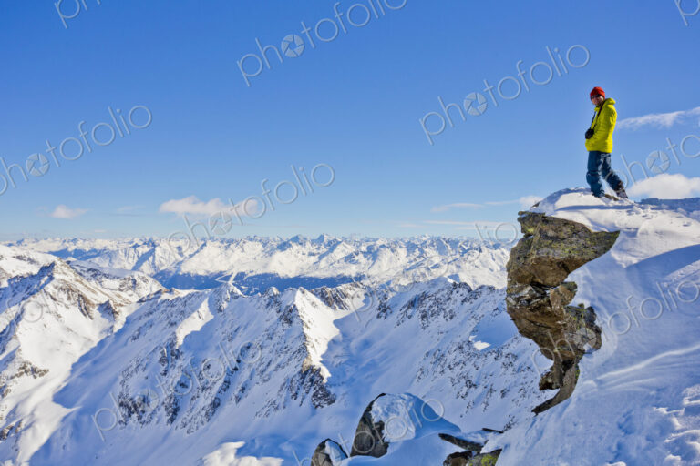 Hiker admiring scenic view from snowy mountaintop