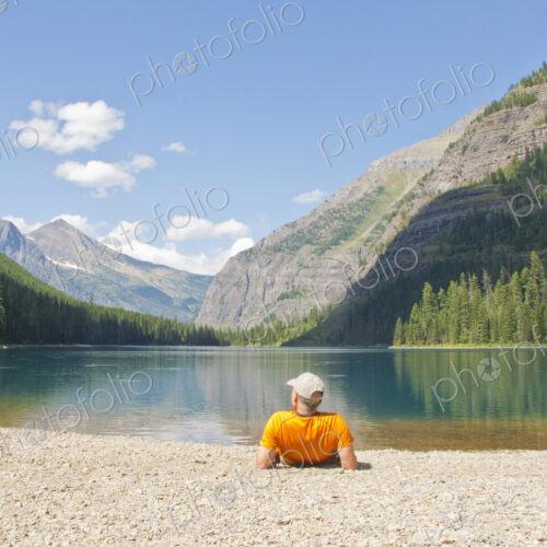 Hiker laying near mountain lake, Glacier National Park, Montana, United States Hiker laying near mountain lake, Glacier National Park, Montana, United States