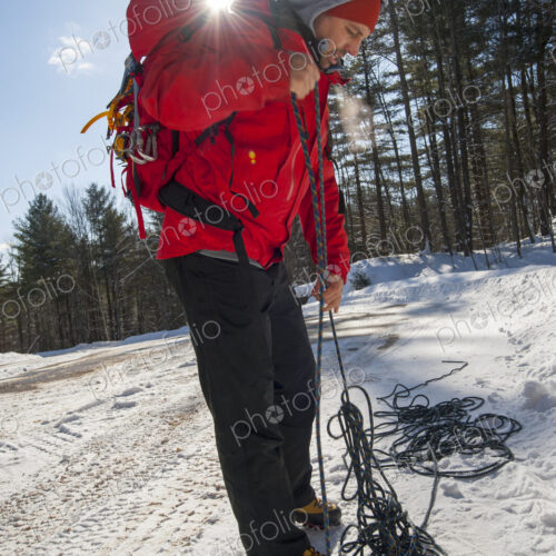 Hiker untangling ropes in snowy forest