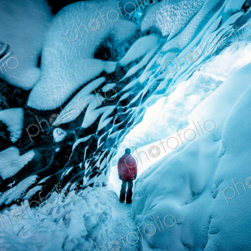 Hiker walking in ice cave Hiker walking in ice cave