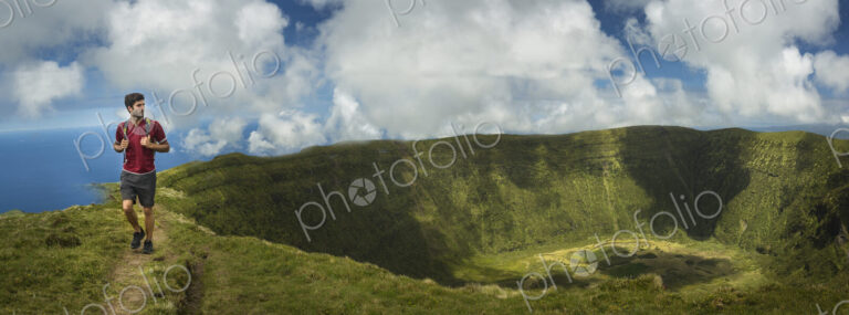 Hiker walking on hilltop dirt path over Cabeco Gordo crater, Faial, Portugal