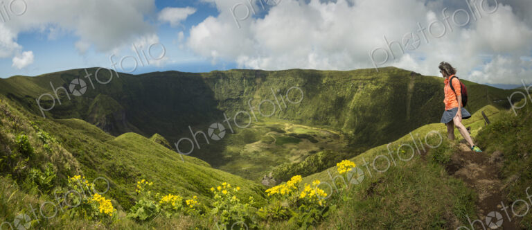 Hiker walking on hilltop dirt path over Cabeco Gordo crater, Faial, Portugal