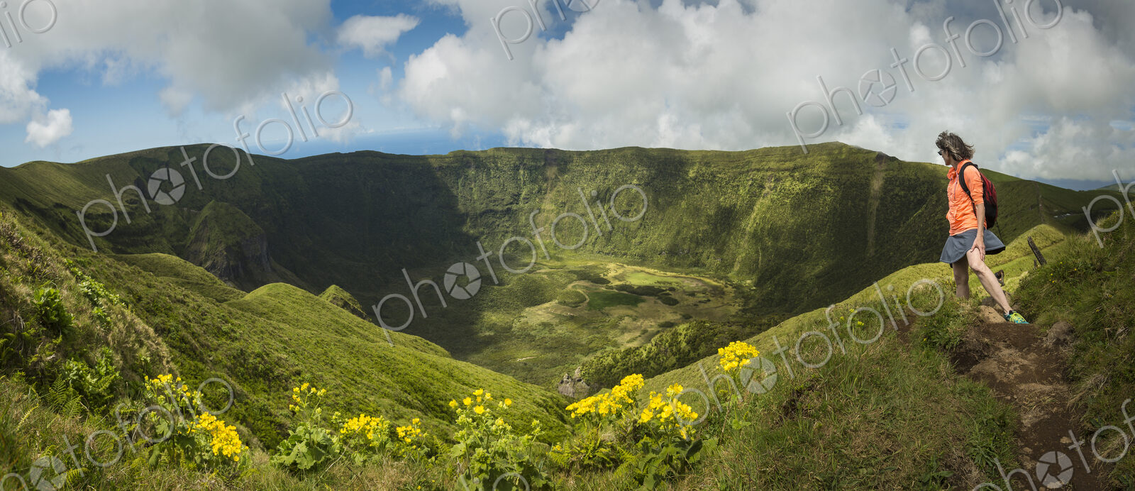 Hiker walking on hilltop dirt path over Cabeco Gordo crater, Faial, Portugal