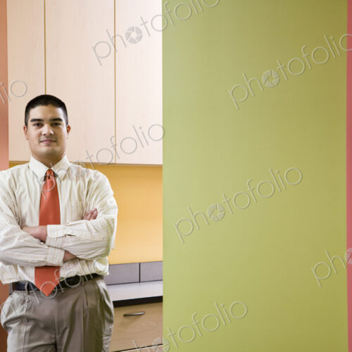Hispanic busienssman in a shirt and tie standing next to colorful walls in an office. Hispanic busienssman in a shirt and tie standing next to colorful walls in an office.