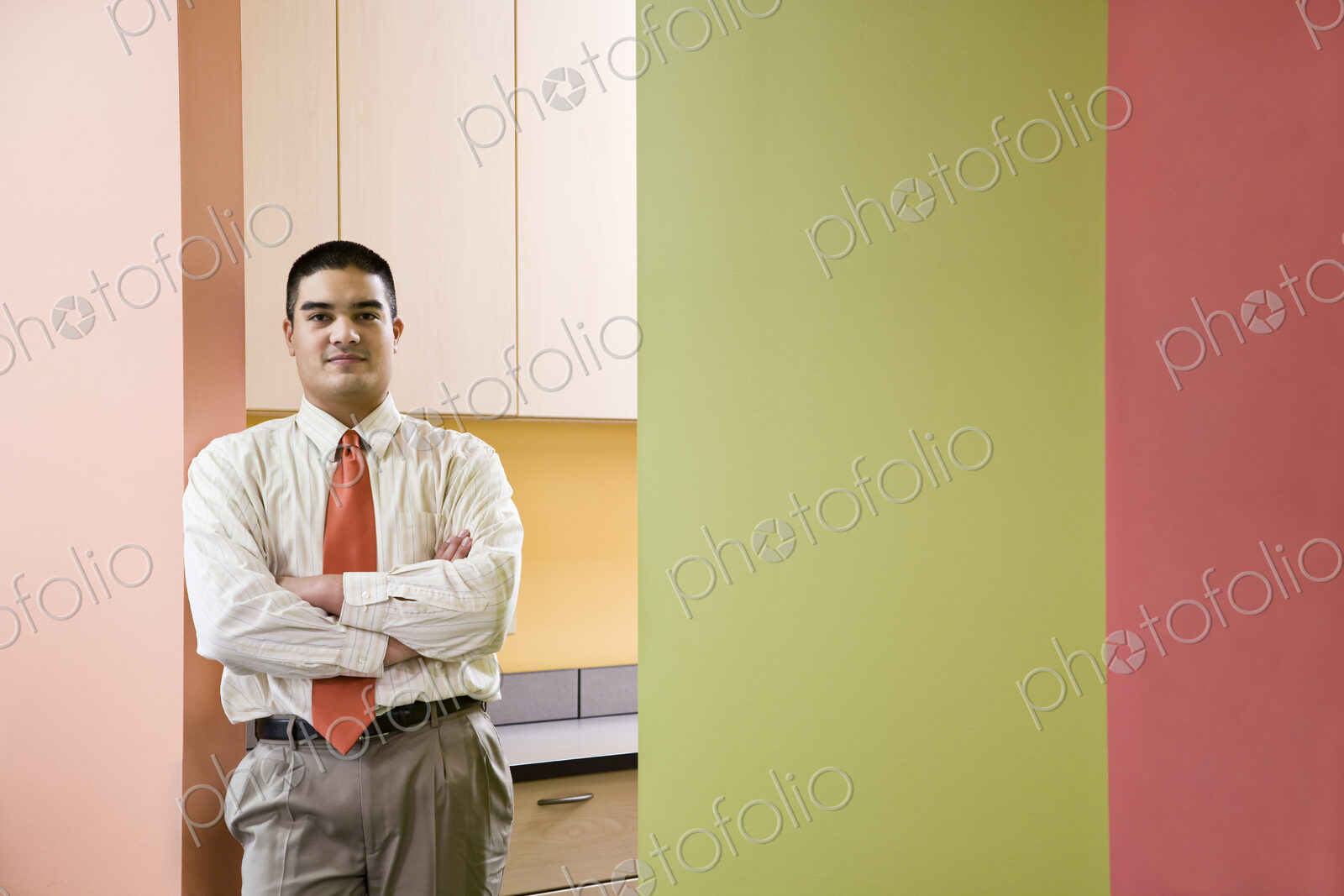 Hispanic busienssman in a shirt and tie standing next to colorful walls in an office.