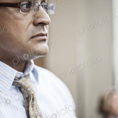 Hispanic busiessman in a shirt and tie standing in a convention center space.