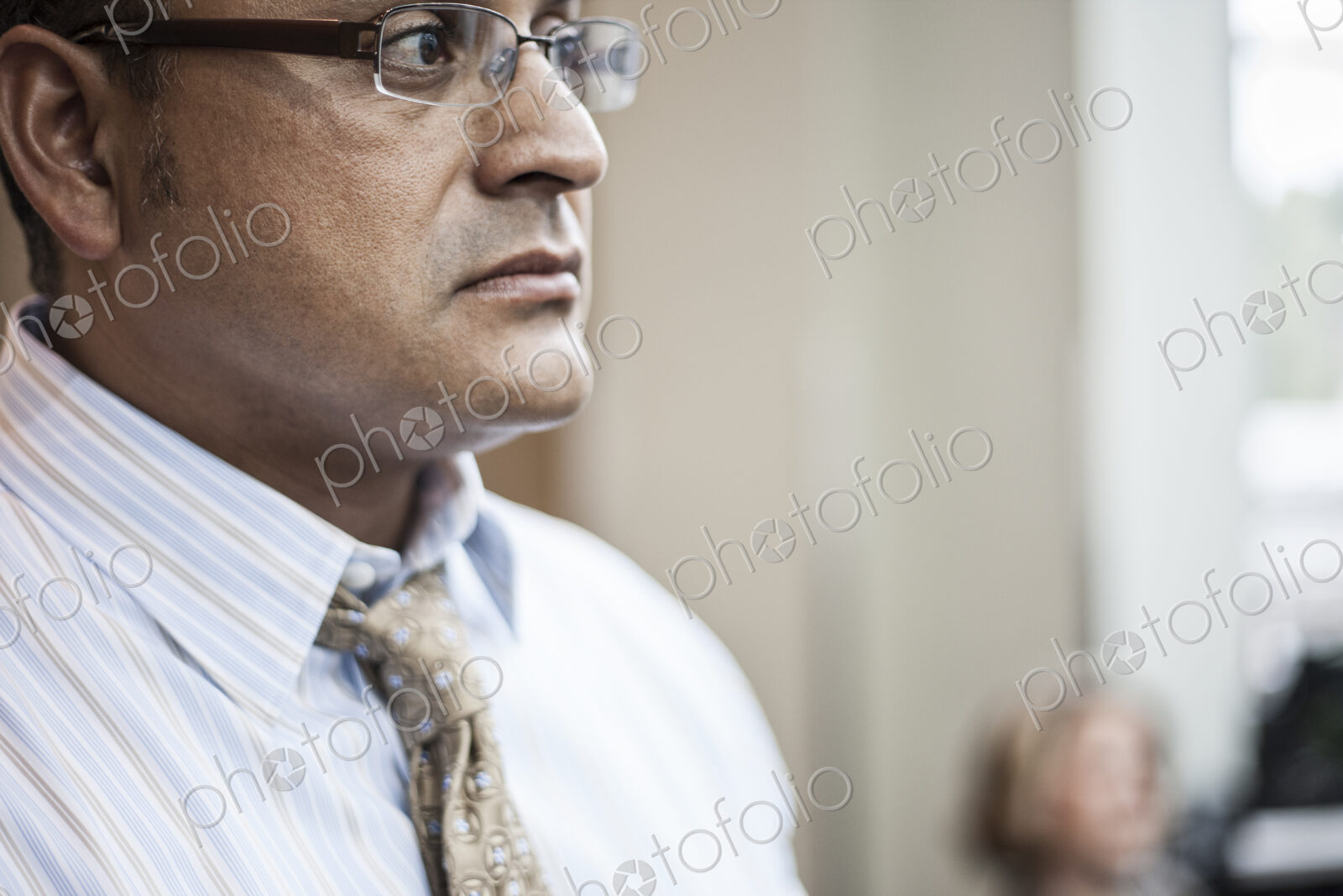 Hispanic busiessman in a shirt and tie standing in a convention center space.