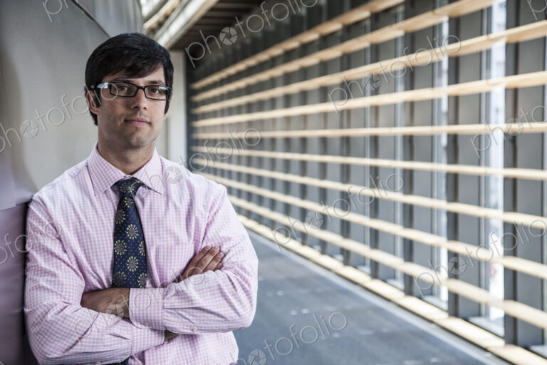 Hispanic business man standing in an office lobby.