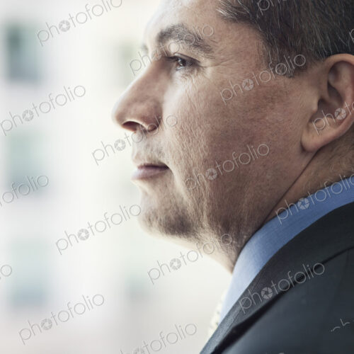 Hispanic businessman looking out the window of a conference centre lobby.