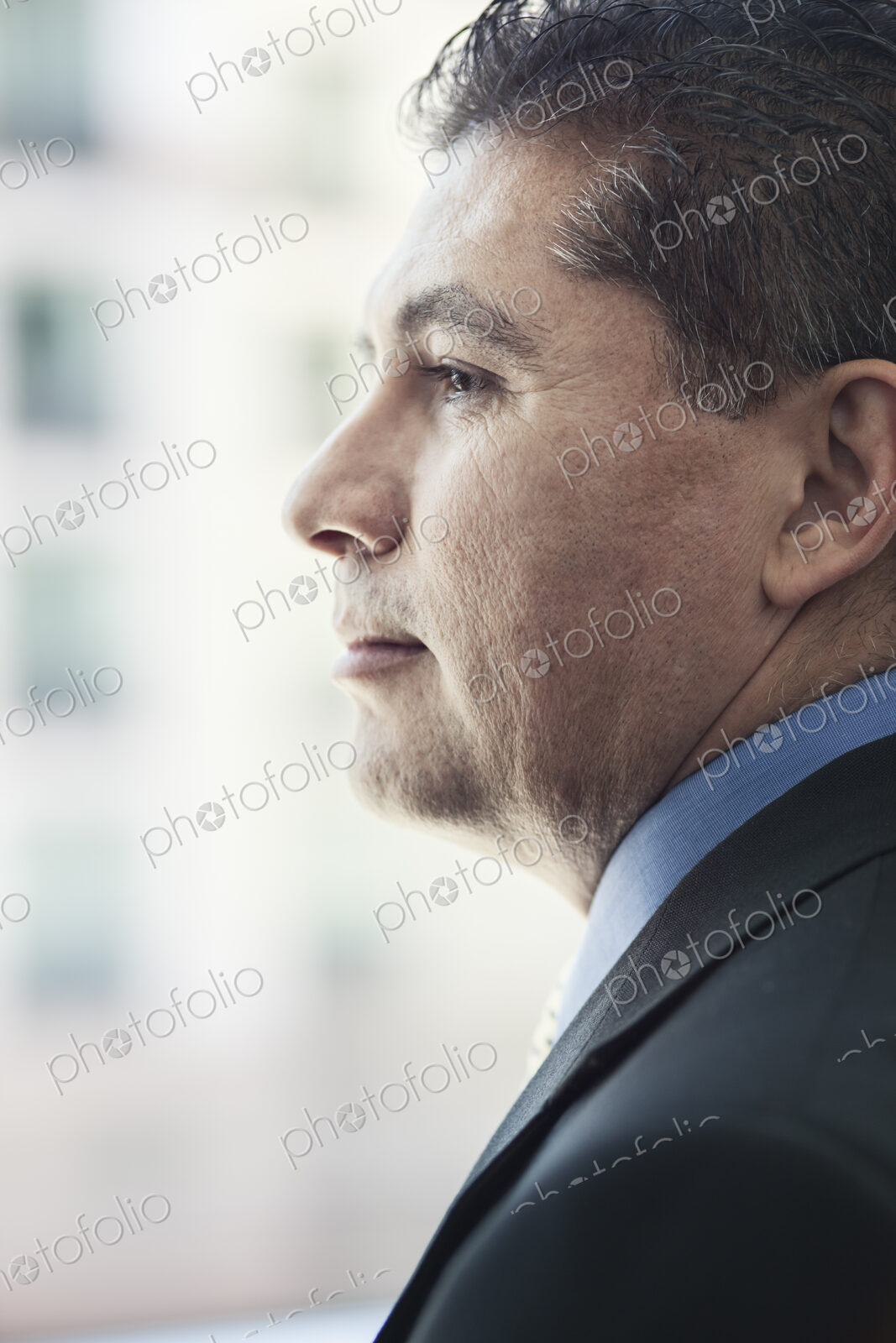 Hispanic businessman looking out the window of a conference centre lobby.