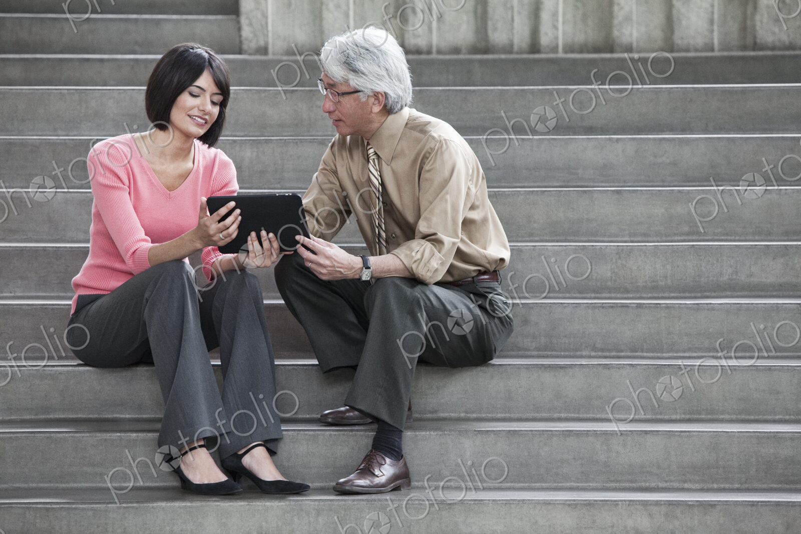Hispanic businesswoman and Asian businessman working on a notebook computer