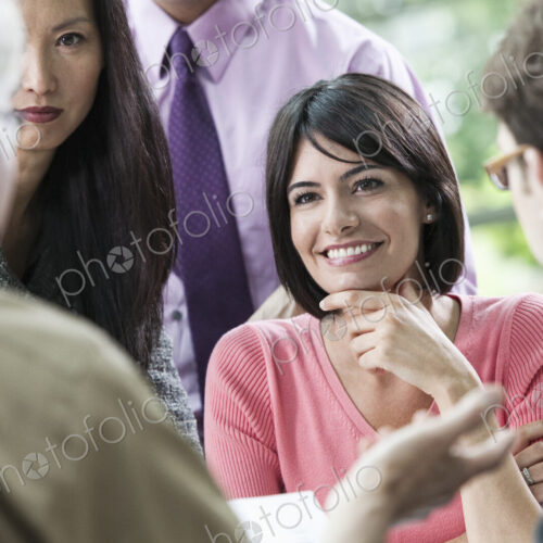 Hispanic businesswoman listening to someone talk during a business meeting with other… Hispanic businesswoman listening to someone talk during a business meeting with other…