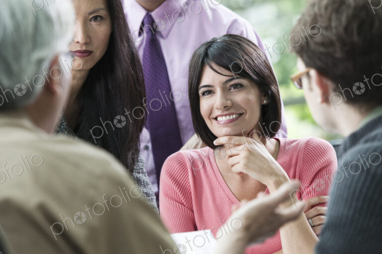 Hispanic businesswoman listening to someone talk during a business meeting with other…