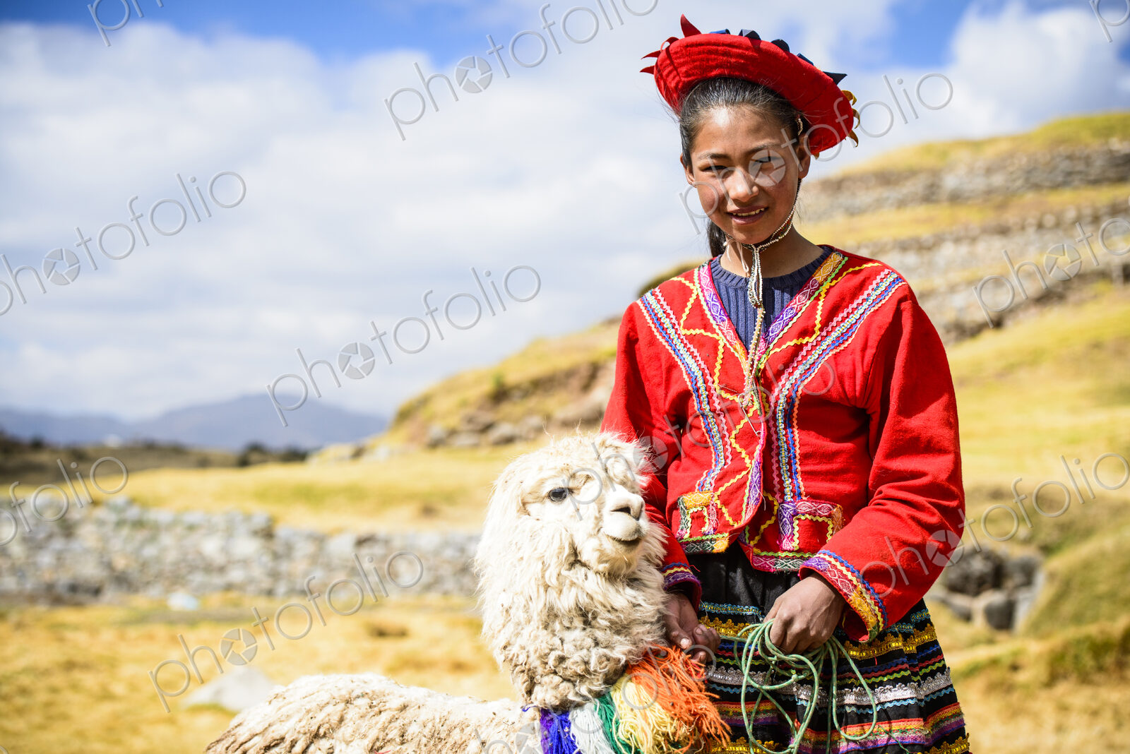 Hispanic girl walking llama in rural landscape