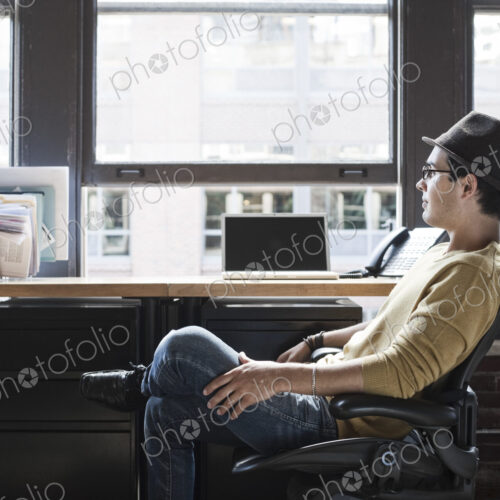 Hispanic male at his office workstation in a creative office. Hispanic male at his office workstation in a creative office.
