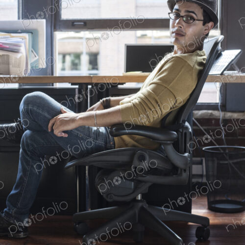 Hispanic male at his office workstation in a creative office. Hispanic male at his office workstation in a creative office.