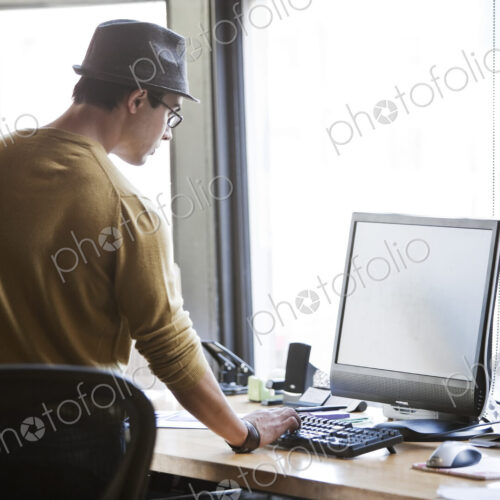 Hispanic male at his office workstation in a creative office.