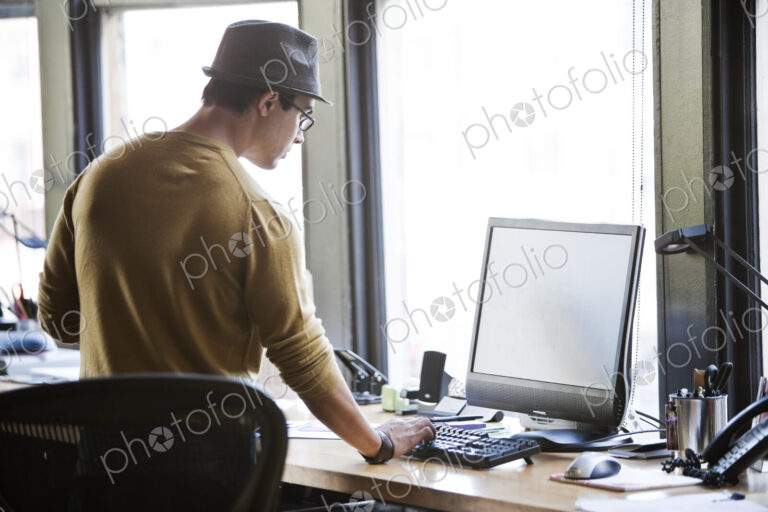 Hispanic male at his office workstation in a creative office.