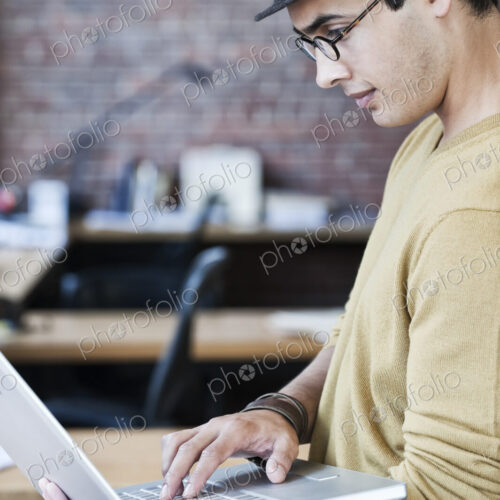 Hispanic male at his office workstation in a creative office. Hispanic male at his office workstation in a creative office.