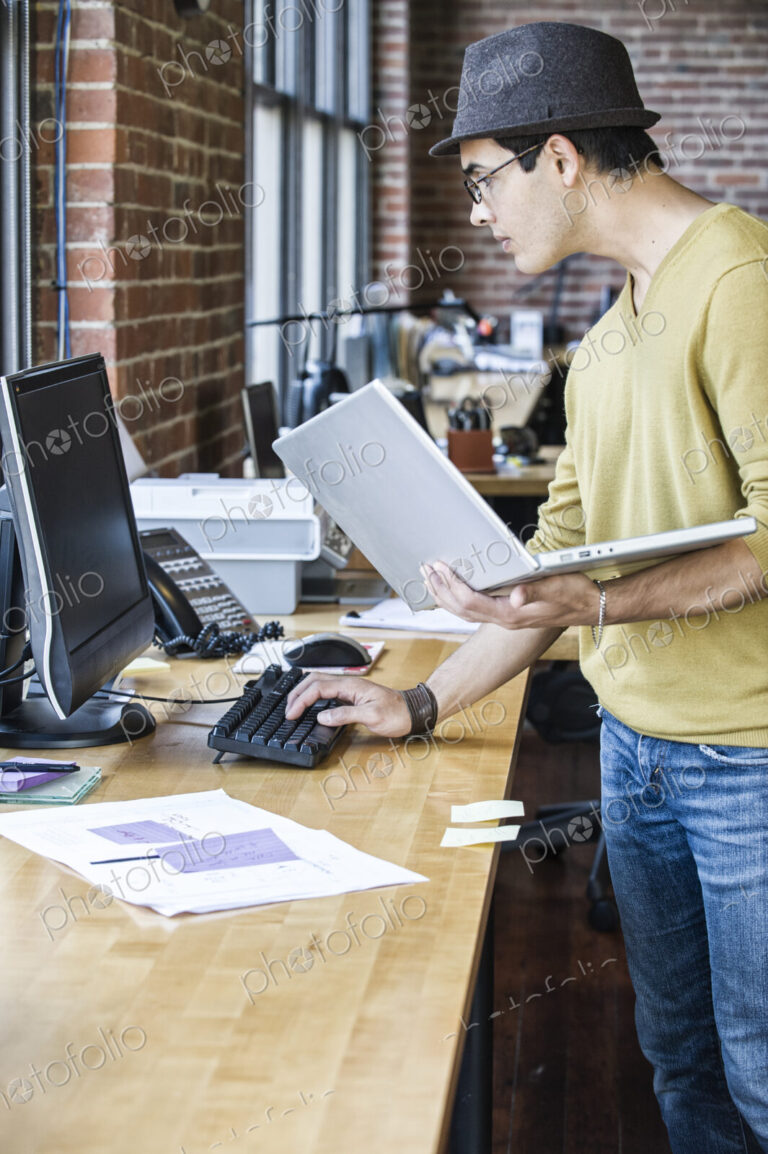 Hispanic male at his office workstation in a creative office.