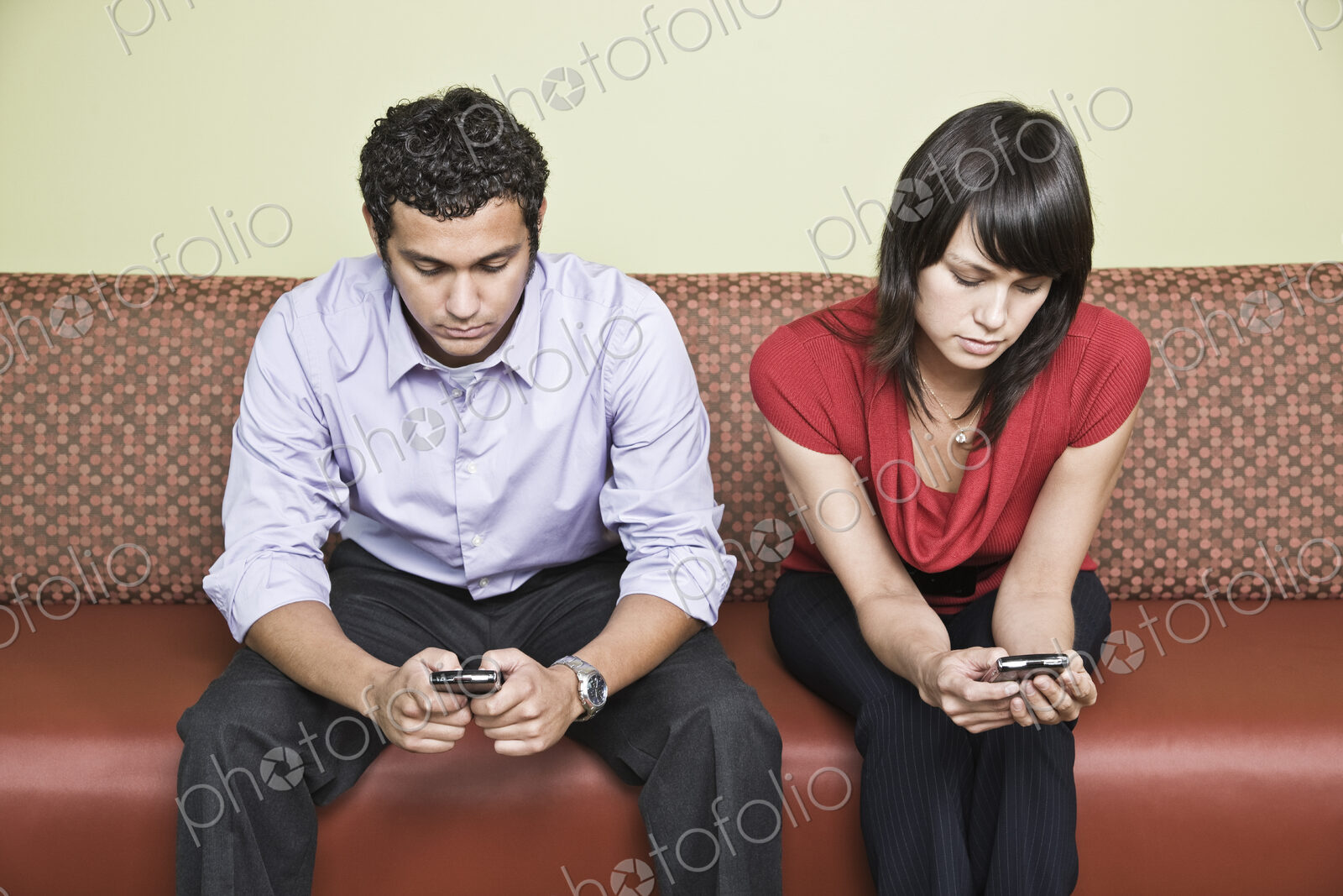 Hispanic man and caucasian woman each on a cell phone in an office.