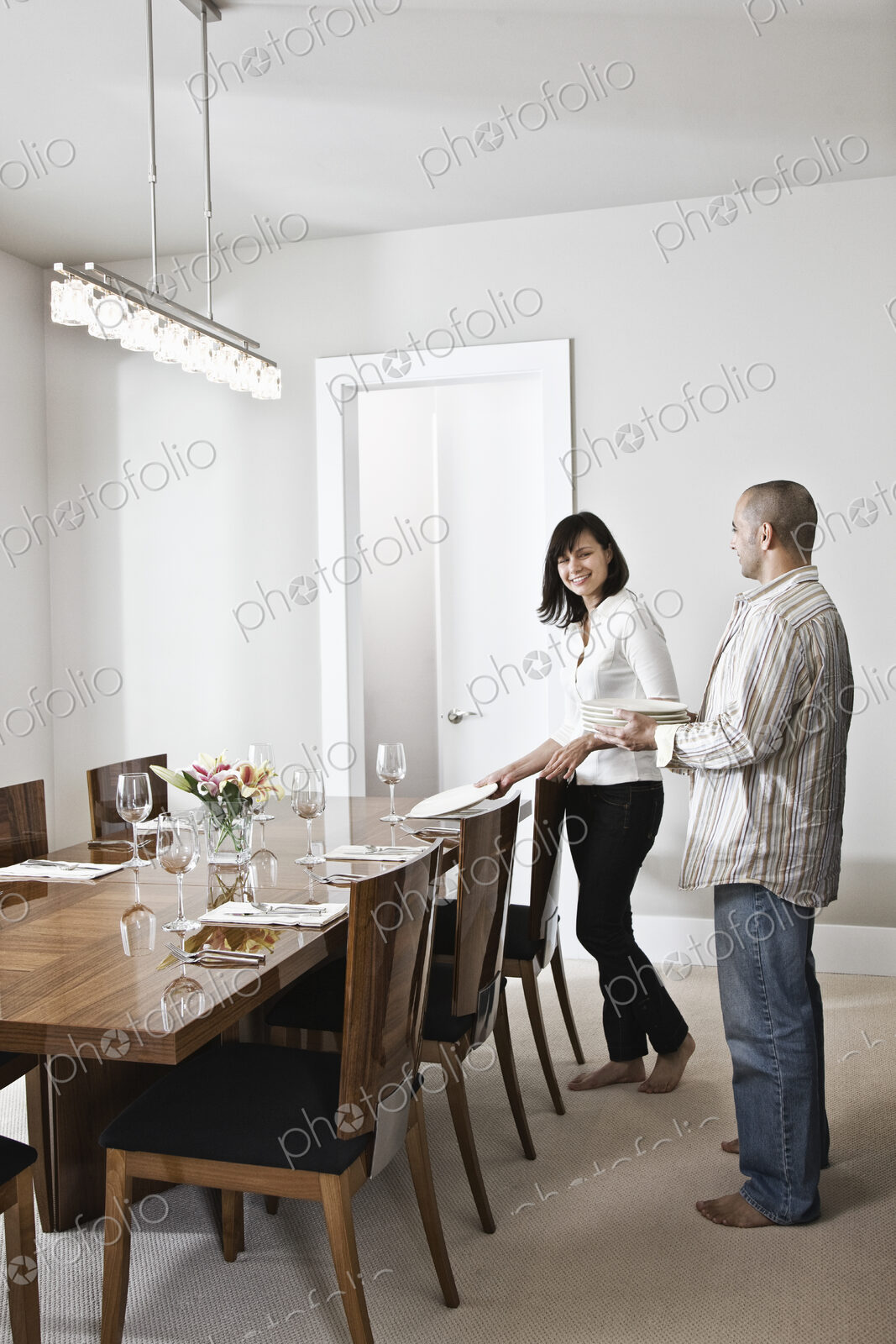 Hispanic man and woman doing place settings at their dinning room table in a new home.