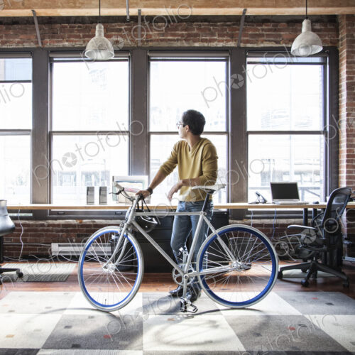 Hispanic man at his office workstation with a bicycle. Hispanic man at his office workstation with a bicycle.