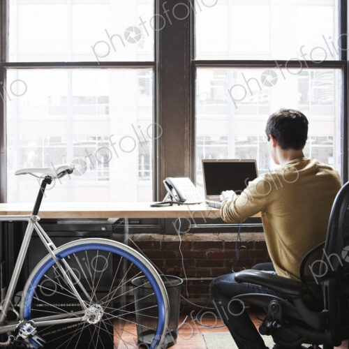 Hispanic man at his office workstation with a bicycle. Hispanic man at his office workstation with a bicycle.