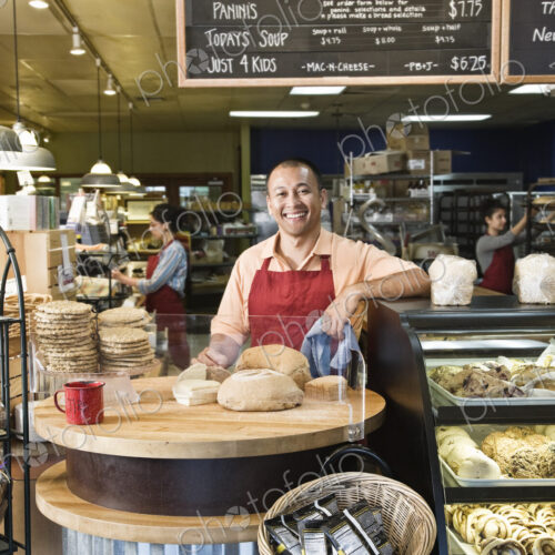 Hispanic man baker and employees in the backgrtound of the bakery. Hispanic man baker and employees in the backgrtound of the bakery.
