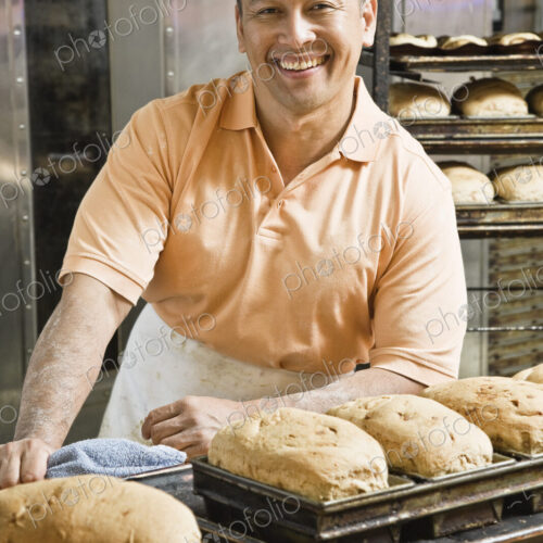 Hispanic man baker and some of the loaves of bread he baked this morning. Hispanic man baker and some of the loaves of bread he baked this morning.