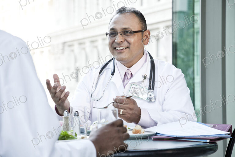 Hispanic man doctor in a lunch discussion with a colleague.