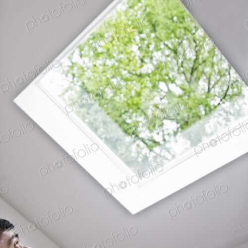 Hispanic man looking up at a skylight in an office. Hispanic man looking up at a skylight in an office.