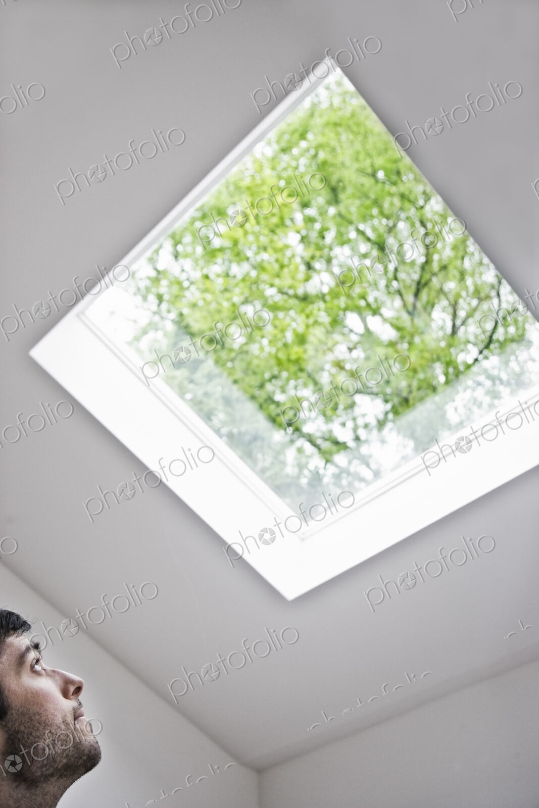 Hispanic man looking up at a skylight in an office.