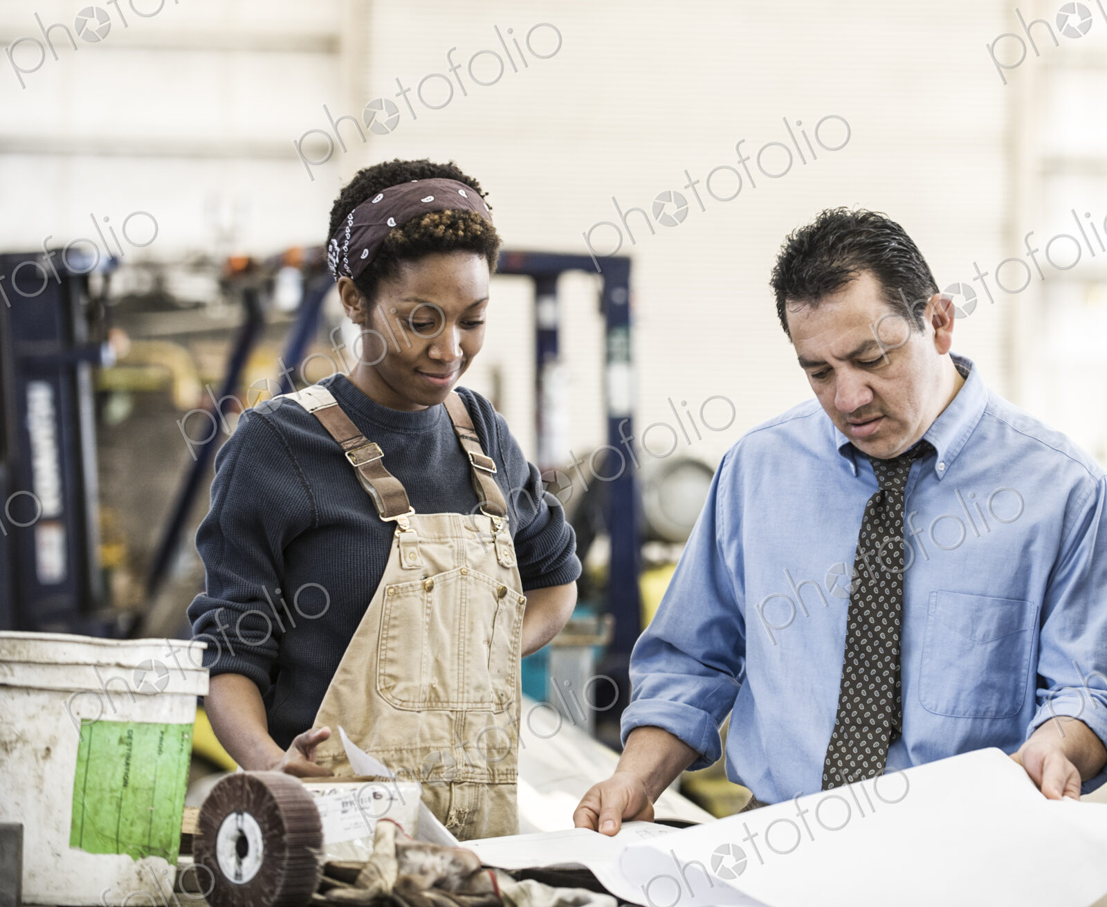 Hispanic man manager and black woman factory worker going over project plans in a…