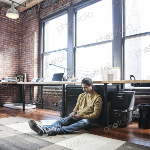 Hispanic man on his cell phone while sitting on floor at his office workstation. Hispanic man on his cell phone while sitting on floor at his office workstation.