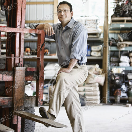 Hispanic man owner of a landscape company standing in the equipment room