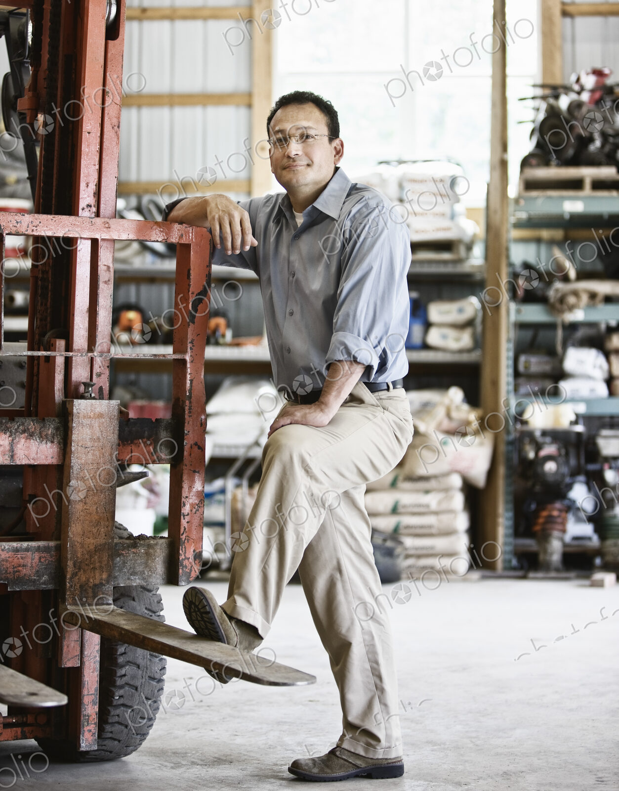 Hispanic man owner of a landscape company standing in the equipment room