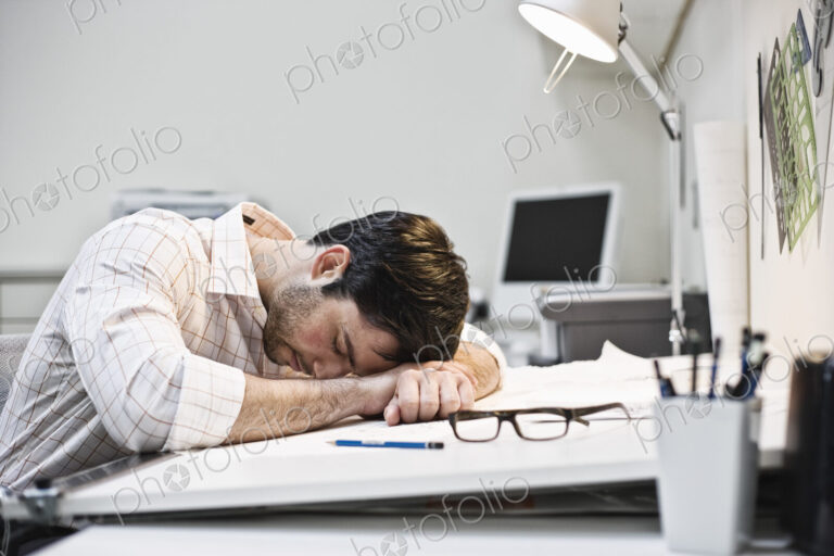 Hispanic man taking a quick nap in an architect's office.
