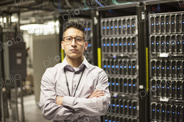 Hispanic man technician doing diagnostic tests on computer servers in a large server farm.