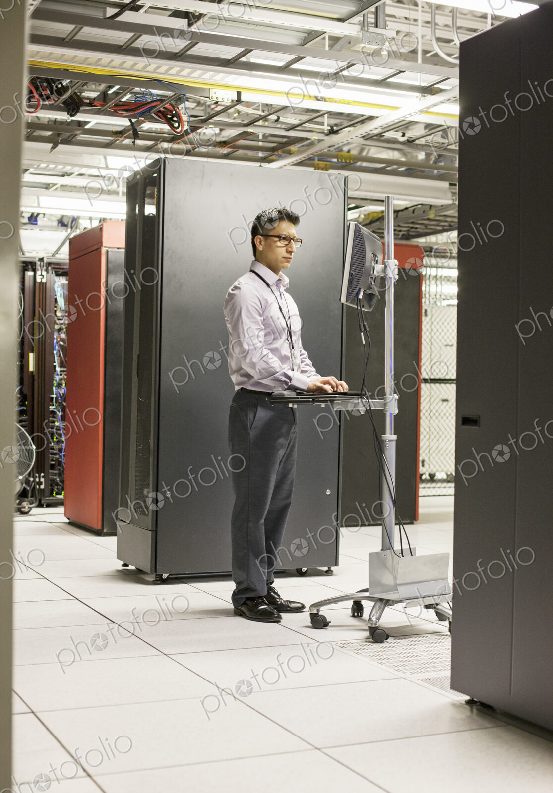Hispanic man technician doing diagnostic tests on computer servers in a large server farm.