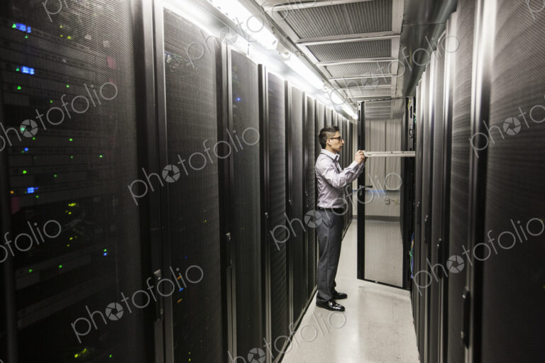 Hispanic man technician doing diagnostic tests on computer servers in a large server farm.