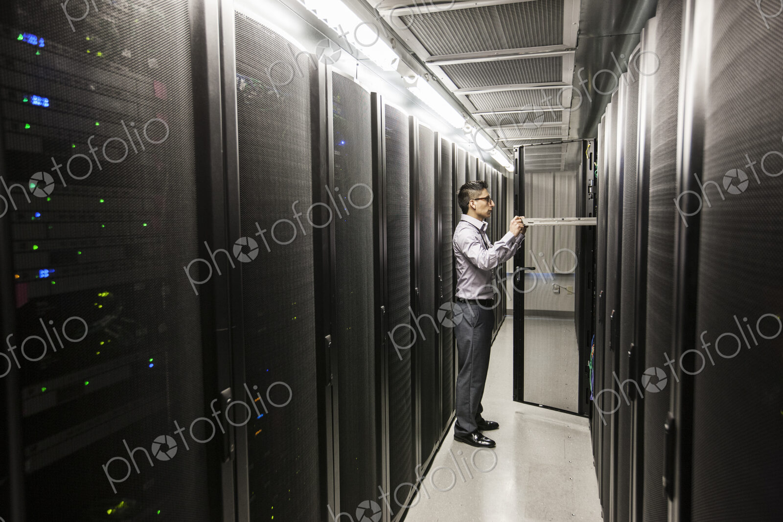 Hispanic man technician doing diagnostic tests on computer servers in a large server farm.