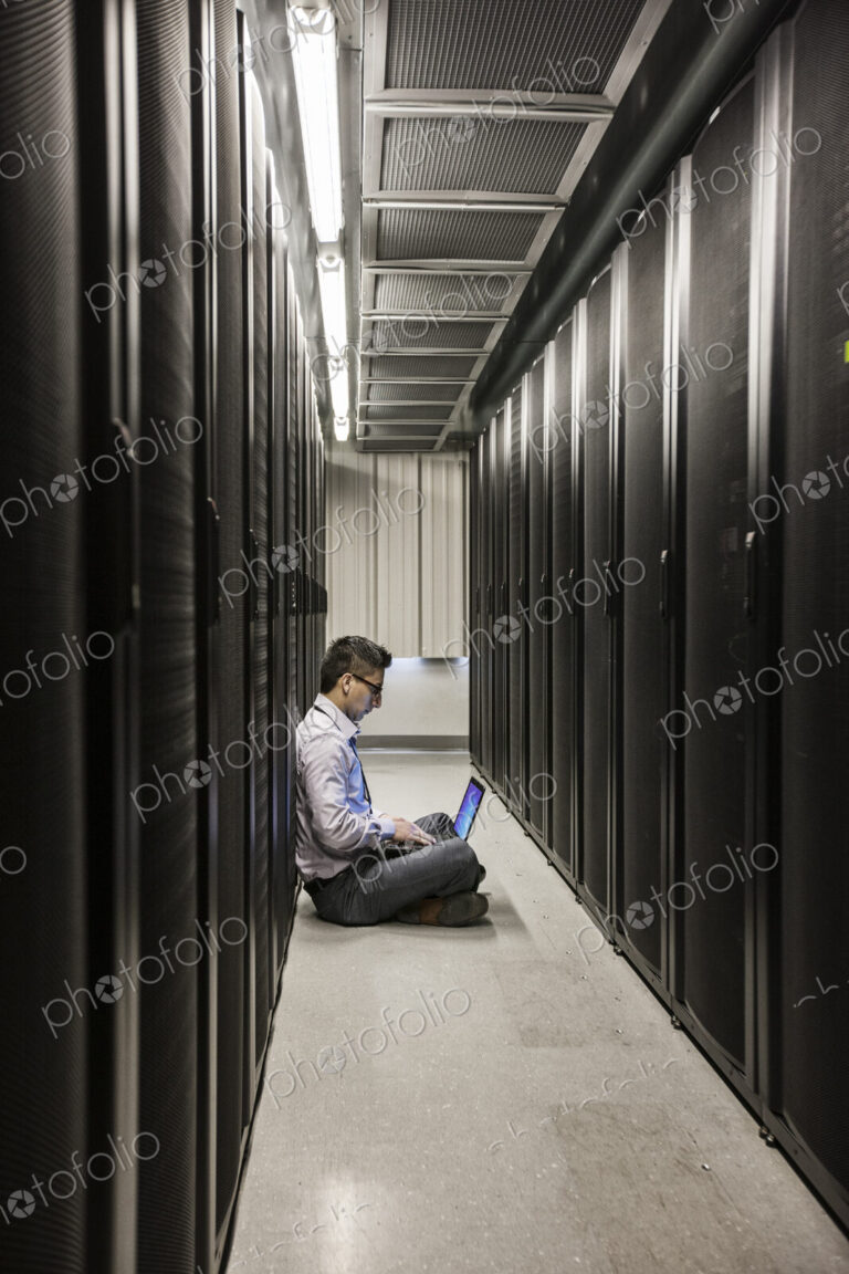 Hispanic man technician doing diagnostic tests on computer servers in a large server farm.