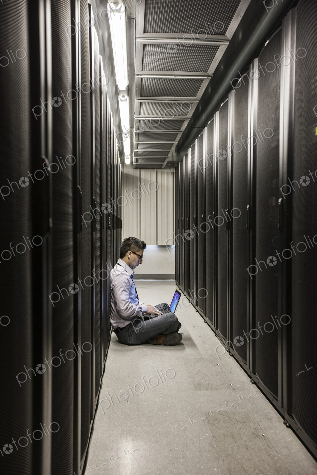 Hispanic man technician doing diagnostic tests on computer servers in a large server farm.